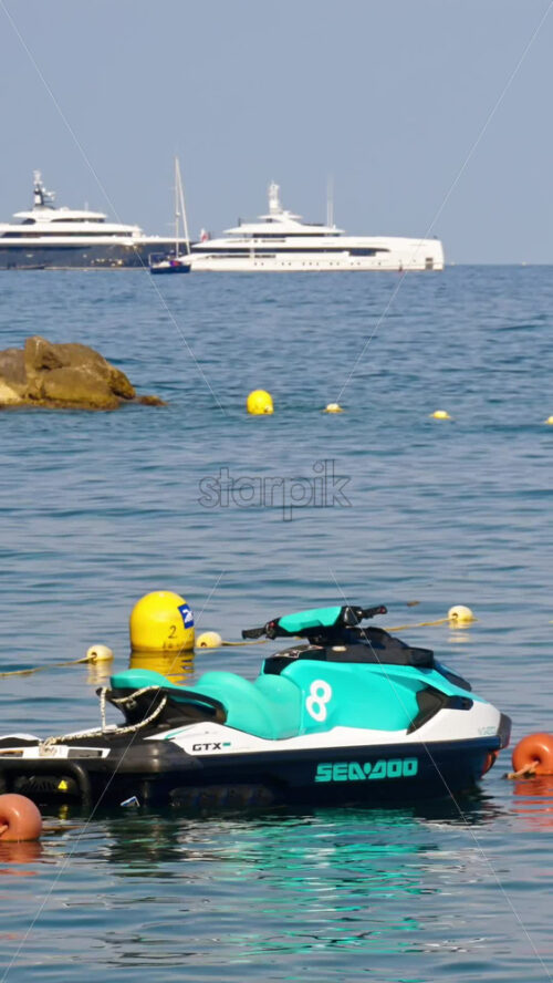 Video - Beaulieu-sur-Mer, France - July 5, 2024: Turquoise Jet Ski on the sea, with boats docked on the background. Vertical