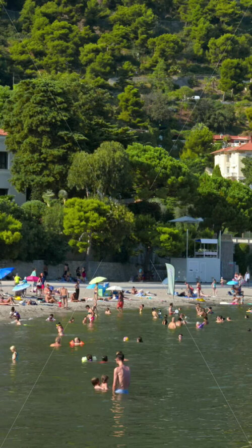 Video - Beaulieu-sur-Mer, France - July 5, 2024: People swimming and relaxing at the Petite Afrique Beach. Vertical