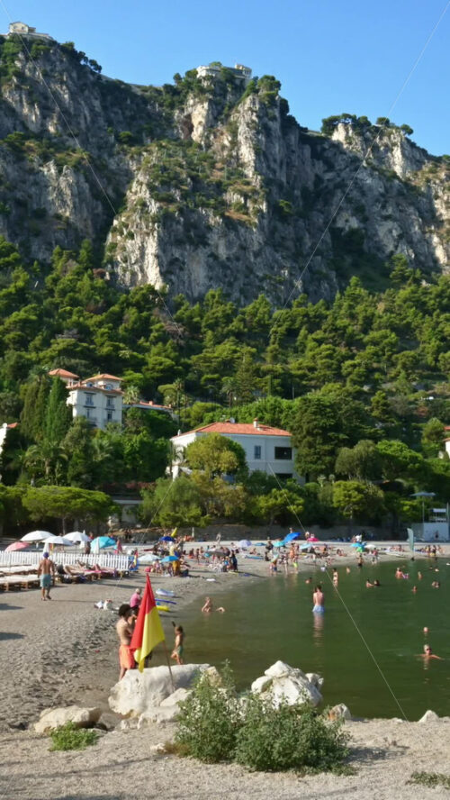 Video - Beaulieu-sur-Mer, France - July 5, 2024: People swimming and relaxing at the Petite Afrique Beach. Vertical