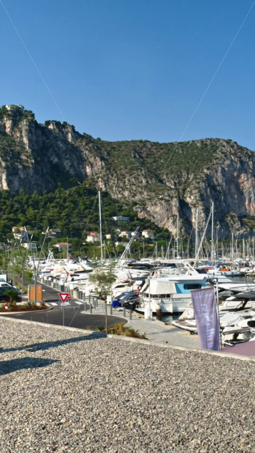Video - Beaulieu-sur-Mer, France - July 5, 2024: Boats docked in the port with the mountains on the background. Vertical