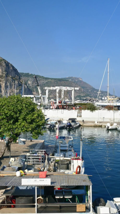 Video - Beaulieu-sur-Mer, France - July 5, 2024: Boats docked in the port with the mountains on the background. Vertical