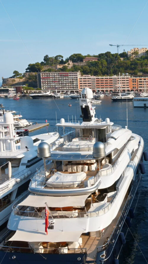 Video - View of white boats docked in the Monaco Marina with the skyline of the city on the background. Vertical