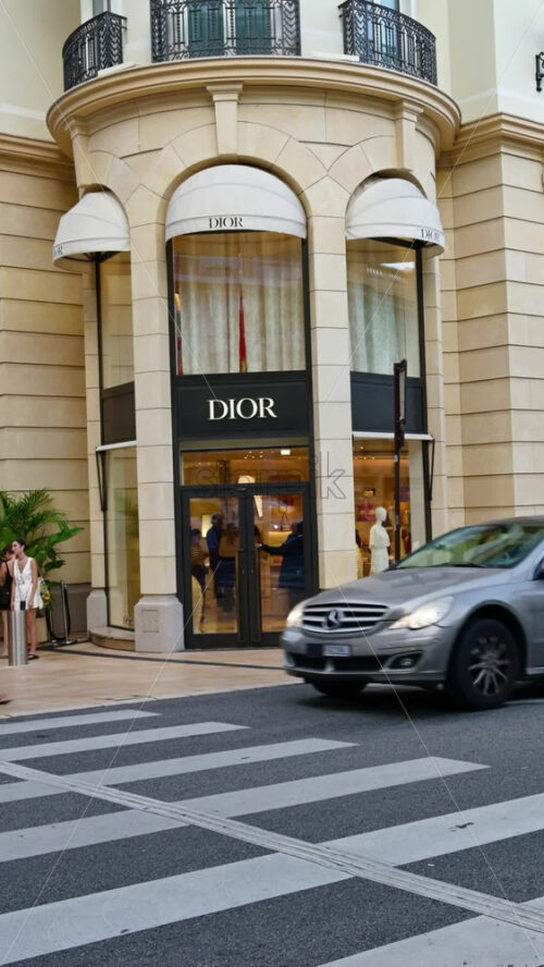 Video - Monte Carlo, Monaco - October 4, 2024: Luxury stores on a street in the city with people and cars moving around. Vertical