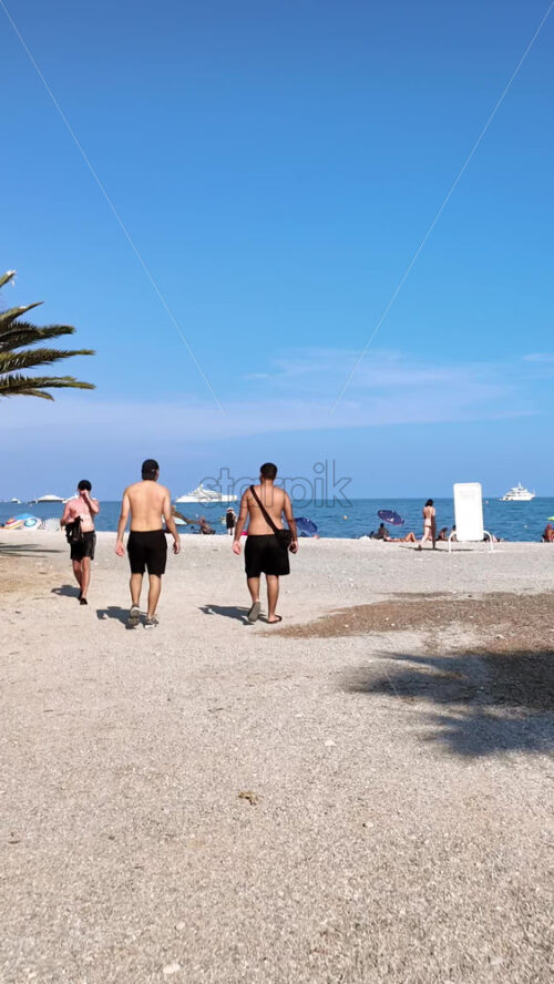 Video - Beaulieu-sur-Mer, France - July 5, 2024: People walking on the beach and relaxing in the sea at the Petite Afrique Beach. Vertical