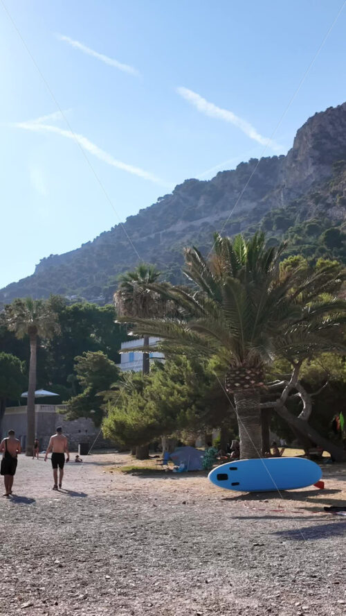 Video - Beaulieu-sur-Mer, France - July 5, 2024: People walking on the beach and relaxing in the sea at the Petite Afrique Beach. Vertical