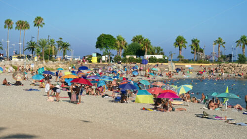Video - Menton, France - September 4, 2024: People swimming and relaxing on the beach under sun umbrellas