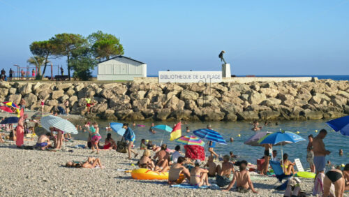 Video - Menton, France - September 4, 2024: People swimming and relaxing on the beach under sun umbrellas