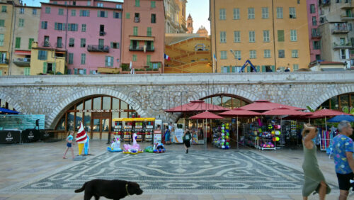 Video - Menton, France - September 4, 2024: View of the colourful buildings in the city and people walking by the coastline