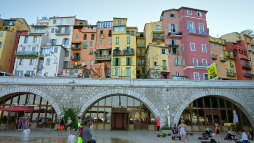 Video - Menton, France - September 4, 2024: View of the colourful buildings in the city and people walking by the coastline