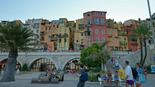 Video - Menton, France - September 4, 2024: View of the colourful buildings in the city and people walking by the coastline