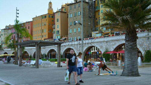 Video - Menton, France - September 4, 2024: View of the colourful buildings in the city and people walking by the coastline