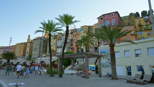 Video - Menton, France - September 4, 2024: View of the colourful buildings in the city and people walking by the coastline