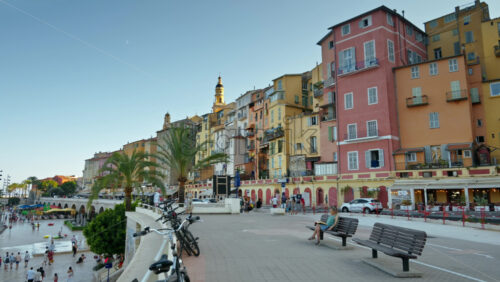 Video - Menton, France - September 4, 2024: View of the colourful buildings in the city and people walking by the coastline