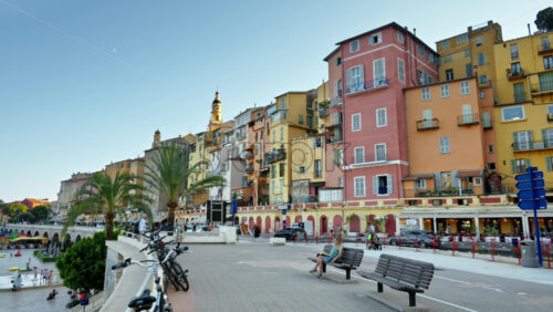 Video - Menton, France - September 4, 2024: View of the colourful buildings in the city and people walking by the coastline
