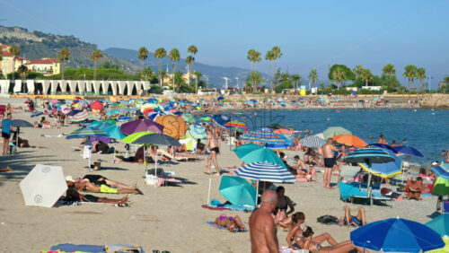 Video - Menton, France - September 4, 2024: People swimming and relaxing on the beach under sun umbrellas