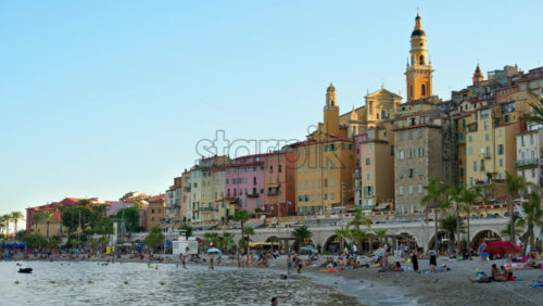 Video - Menton, France - September 4, 2024: People swimming in the sea with a view of the colourful buildings in the city