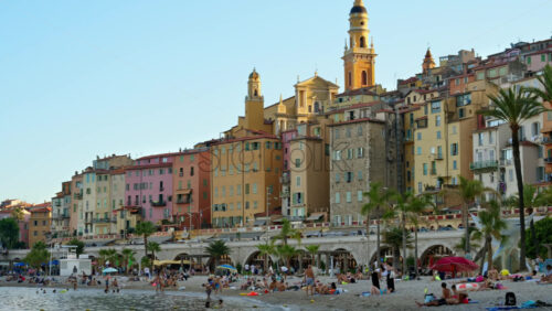 Video - Menton, France - September 4, 2024: People swimming in the sea with a view of the colourful buildings in the city