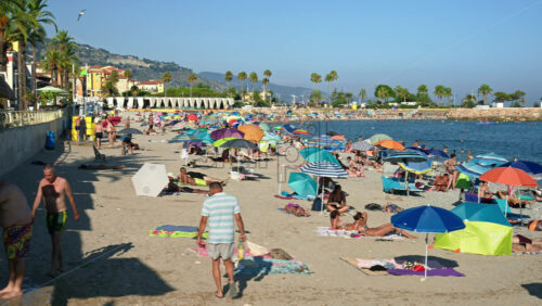 Video - Menton, France - September 4, 2024: People swimming and relaxing on the beach under sun umbrellas