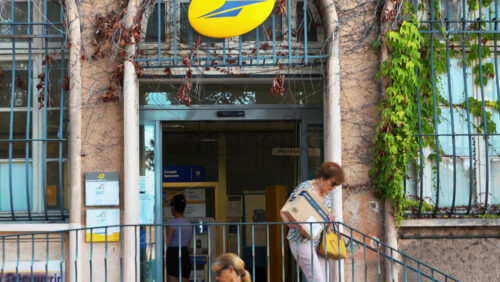 Video - Menton, France - September 4, 2024: Woman walking out a Post office with a package in daylight