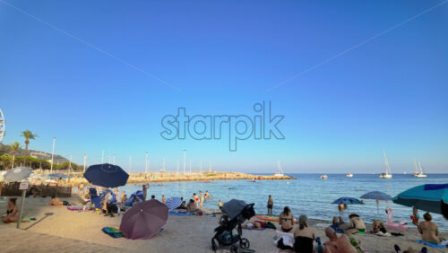 Video - Menton, France - September 4, 2024: People swimming and relaxing on the beach under sun umbrellas
