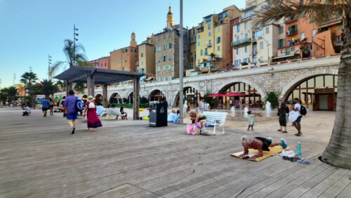 Video - Menton, France - September 4, 2024: View of the colourful buildings in the city and people walking by the coastline