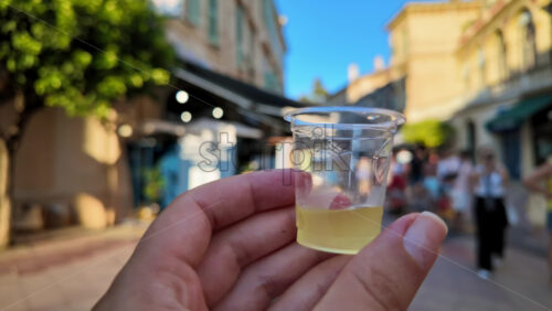 Video - Close up of a woman's hand holding a shot of limoncello on the streets of Menton, France