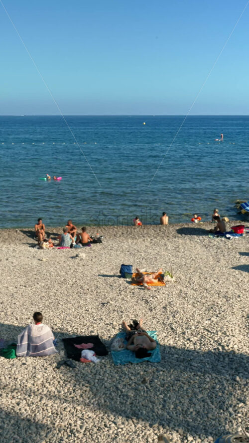 Video - Menton, France - September 4, 2024: People swimming and relaxing on the beach. Vertical