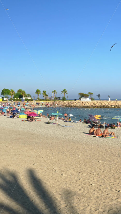 Video - Menton, France - September 4, 2024: People swimming and relaxing on the beach. Vertical