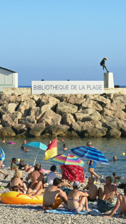 Video - Menton, France - September 4, 2024: People swimming and relaxing on the beach. Vertical