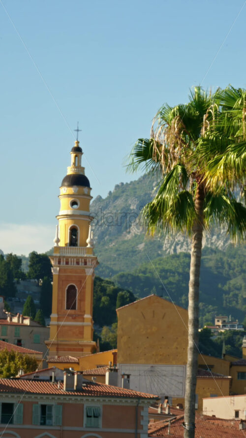 Video - Menton, France - September 4, 2024: Distant view of the St Michel Basilica surrounded by colourful buildings. Vertical