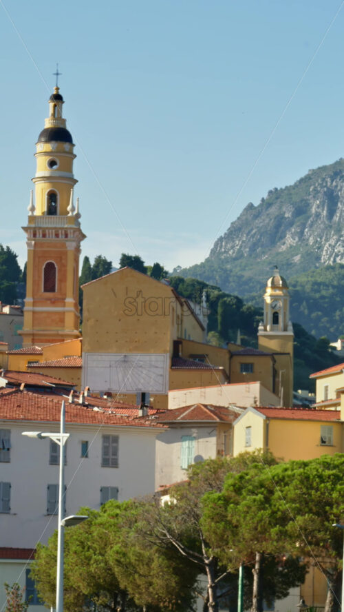 Video - Menton, France - September 4, 2024: Distant view of the St Michel Basilica surrounded by colourful buildings. Vertical