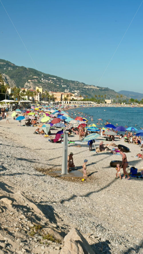 Video - Menton, France - September 4, 2024: People swimming and relaxing on the beach. Vertical