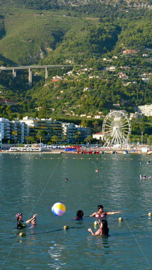 Video - Menton, France - September 4, 2024: People swimming and relaxing on the beach. Vertical