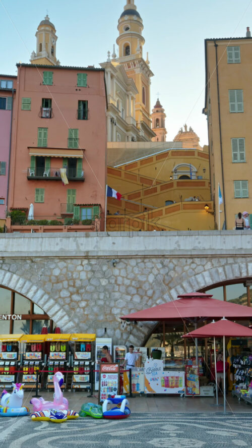 Video - Menton, France - September 4, 2024: View of the colourful buildings in the city and people walking by the coastline. Vertical