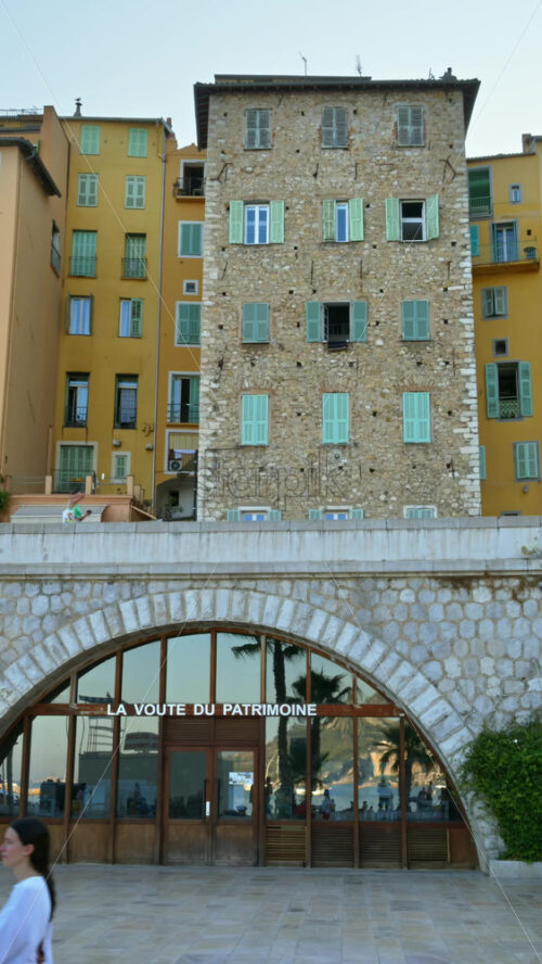Video - Menton, France - September 4, 2024: View of the colourful buildings in the city and people walking by the coastline. Vertical