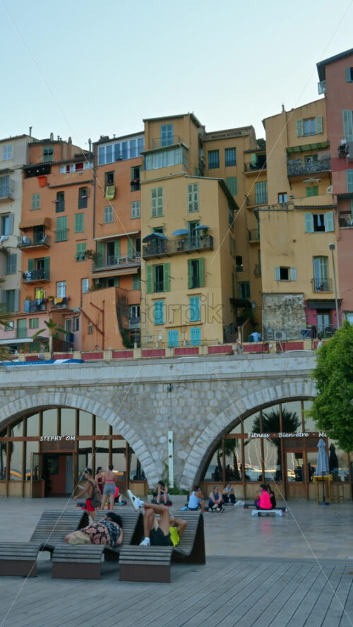 Video - Menton, France - September 4, 2024: View of the colourful buildings in the city and people walking by the coastline. Vertical