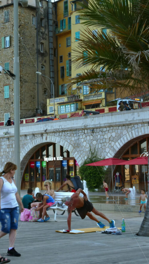Video - Menton, France - September 4, 2024: View of the colourful buildings in the city and people walking by the coastline. Vertical