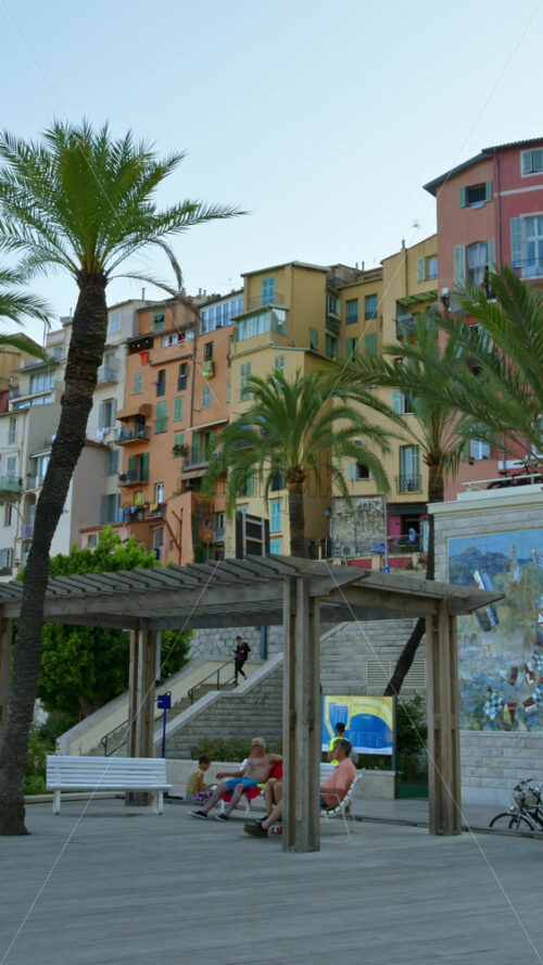 Video - Menton, France - September 4, 2024: View of the colourful buildings in the city and people walking by the coastline. Vertical