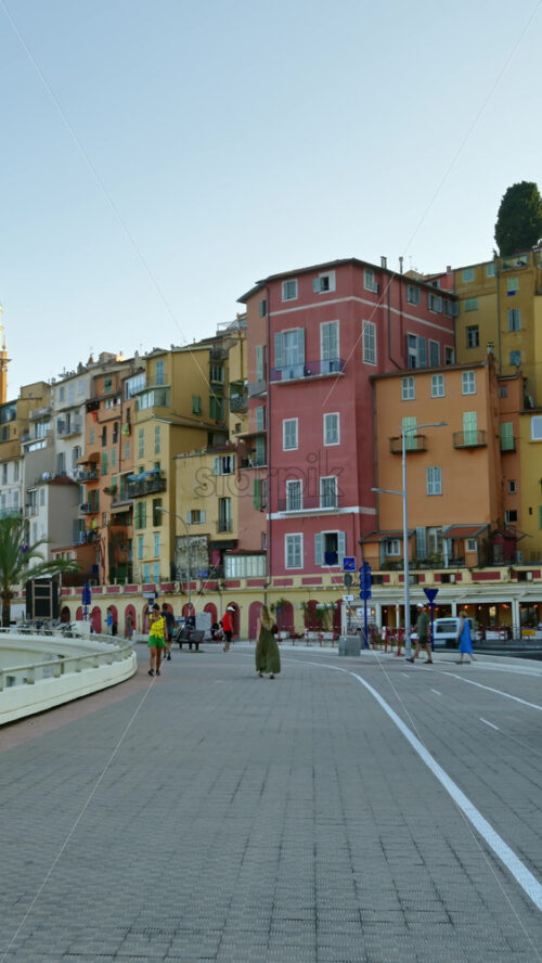 Video - Menton, France - September 4, 2024: View of the colourful buildings in the city and people walking by the coastline. Vertical