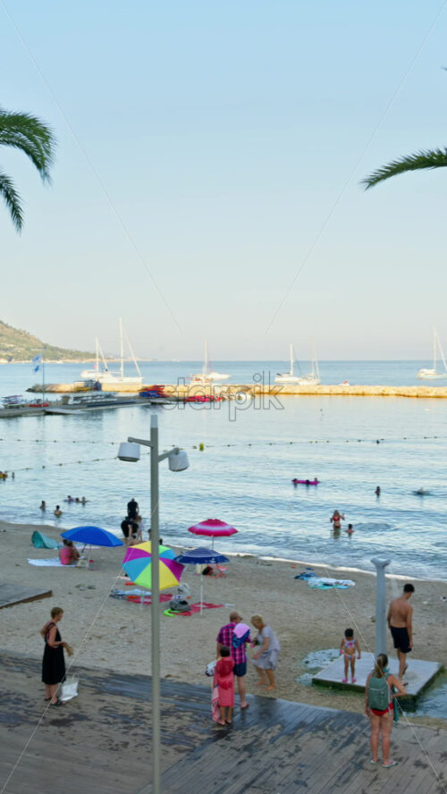 Video - Menton, France - September 4, 2024: People walking and relaxing on the beach in the evening. Vertical