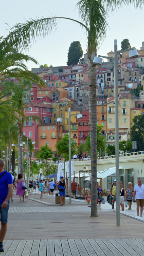 Video - Menton, France - September 4, 2024: View of the colourful buildings in the city and people walking by the coastline. Vertical