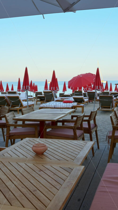 Video - Close up of tables at a restaurant on the beach in the evening. Vertical