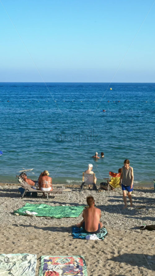 Video - Menton, France - September 4, 2024: People swimming and relaxing on the beach. Vertical