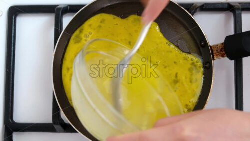 Video - Woman pouring beaten eggs on a pan to make an omelette