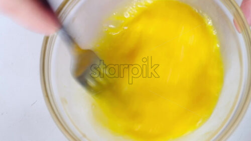 Video - Woman beating eggs with a fork in a glass bowl