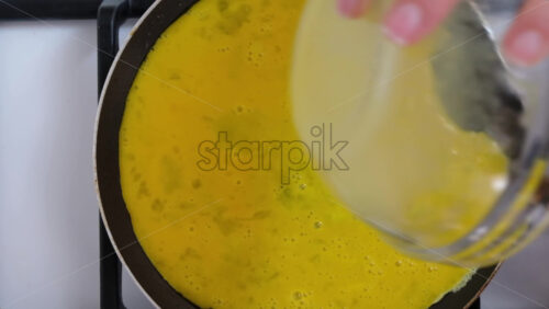 Video - Woman pouring beaten eggs on a pan to make an omelette