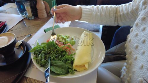 Video - Woman eating an omelette with salad and salmon at a cafe