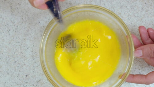 Video - Woman beating eggs with a fork in a glass bowl