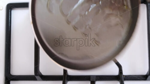 Video - Woman pouring oil in a pan on a white stove