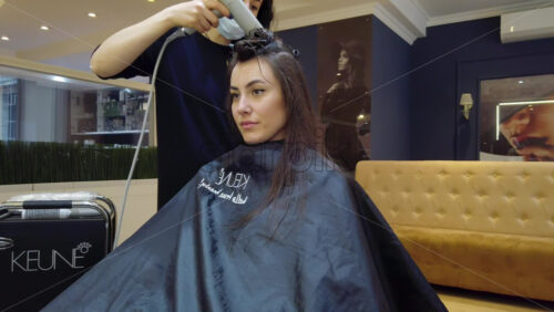 Video - Chisinau, Moldova - April 15, 2021: Hairdresser wearing mask styling woman's hair at the salon